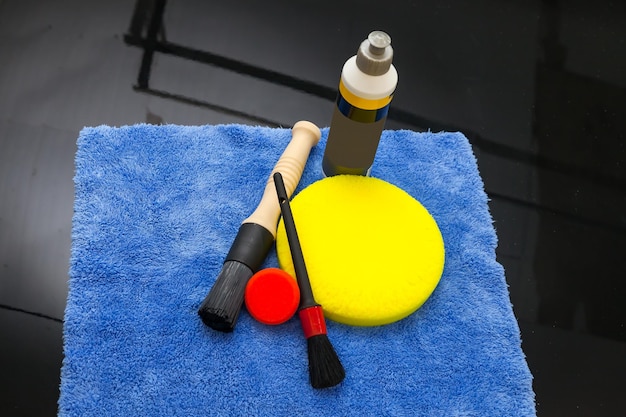 A collection of various car detailing products, including polishing compounds, microfiber towels, clay bars, and ceramic coating applicators, neatly arranged on a workbench. The scene conveys professionalism and preparedness.