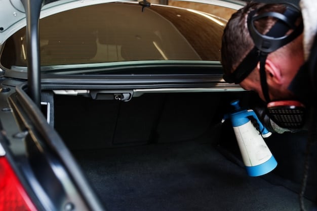 A person carefully applying undercoating to the undercarriage of a car with a spray gun, ensuring even coverage and reaching difficult areas.
