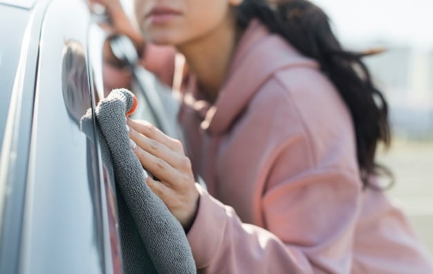 A person's hands buffing a car with a microfiber cloth. The focus is on the cloth and the car's surface, highlighting the reflective shine achieved after buffing.