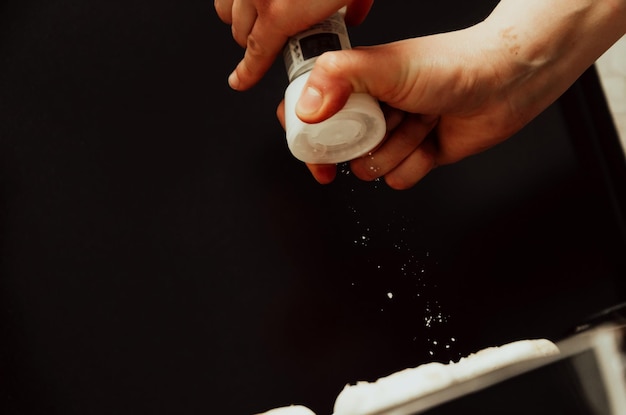 A person sprinkling baking soda over a car seat to absorb odors, illustrating the method described in the article.