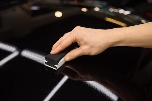 A close-up of a person's hand gently wiping down a car's paint protection film with a microfiber cloth. The surface is glossy and reflective, showcasing the clarity and protective qualities of the film. The background is blurred, emphasizing the care being taken in maintaining the PPF.