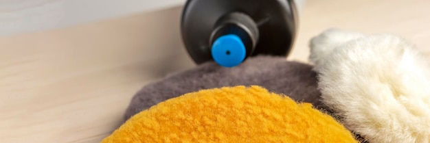Close-up of microfiber cloths in various colors, neatly folded, next to bottles of car wash soap and tire shine, with a focus on the soft texture of the cloths and the cleanliness of the products.