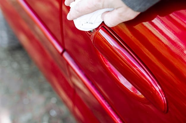 Close-up shot of a car's hood with a clear paint protection film being applied by a professional, ensuring no bubbles or imperfections. The background shows various tools and equipment used in the process.