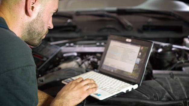 A mechanic using a diagnostic tool connected to a car's onboard computer. The screen displays data related to engine performance and potential issues.