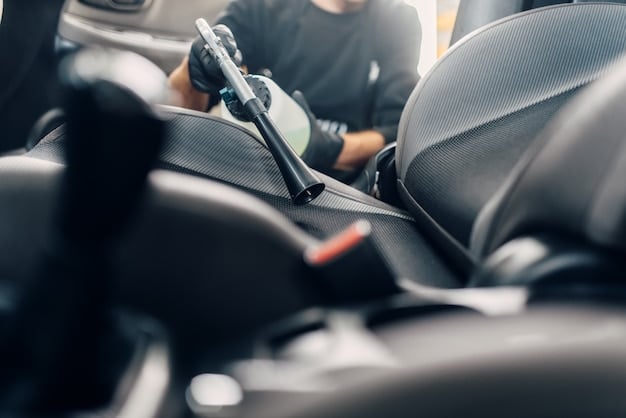 A close-up of a car's dashboard being meticulously cleaned by a professional detailer. The focus is on the detailer's hands and the clean, dust-free surface of the dashboard after cleaning.
