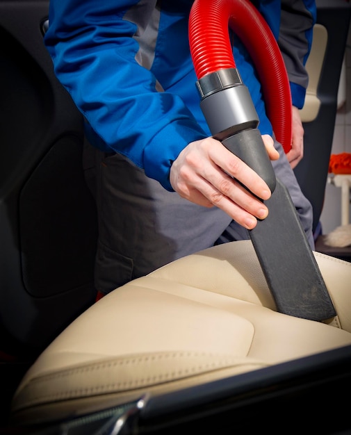 An interior of a car being professionally detailed, with a technician using specialized tools and equipment to clean the upholstery and dashboard.