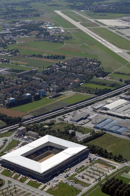 An aerial view of an existing Tesla Gigafactory showing its vast size and the streamlined layout of its production lines. Solar panels cover the roof of the facility.