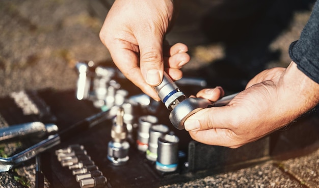 A mechanic inspecting a car's engine, with a close-up view of a clearly fake spark plug. The spark plug has a different color and finish compared to the surrounding genuine parts.