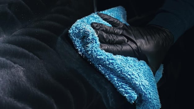 A detailer using a thick plush microfiber towel to gently buff the surface of a car, showing the proper technique and angle to avoid scratches.