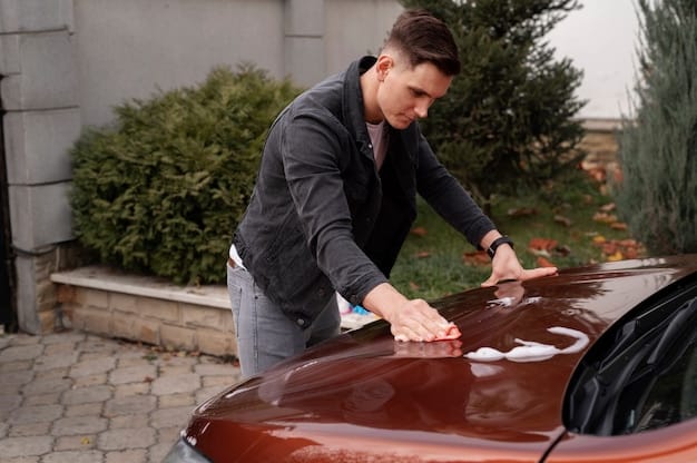 A person carefully using a clay bar on the hood of a car. The clay bar is clean and pliable, and the car's surface is visibly smooth and glossy where the clay bar has been used. A bottle of clay bar lubricant is visible in the background.