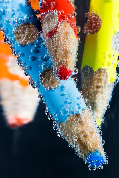 Close-up of car wash soap being poured into a bucket, with water running from a hose. The composition focuses on the suds and the vibrant color of the soap.