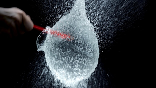 Close-up shot of a wash mitt being rinsed in a bucket of clean water. Dirt and grime can be seen coming off the mitt into the water.