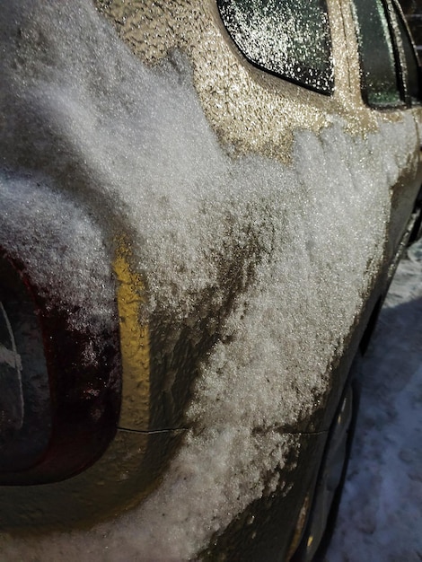 A close-up of a car's surface being cleaned with a clay bar, showing the clay picking up small specks of dirt and contaminants, highlighting the importance of decontamination.
