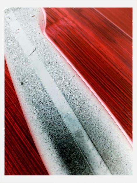 A detailed shot of streaky car paint caused by improper wax application, highlighting the texture and uneven finish under harsh light, serving as a cautionary example.