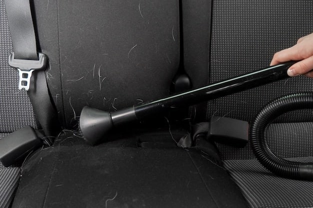 Interior of a car being vacuumed, focusing on the crevice tool attachment cleaning between the seats. The image shows the effectiveness of detailed vacuuming as part of DIY Car Detailing: Interior Cleaning Tips for a Fresh, New Car Feel.