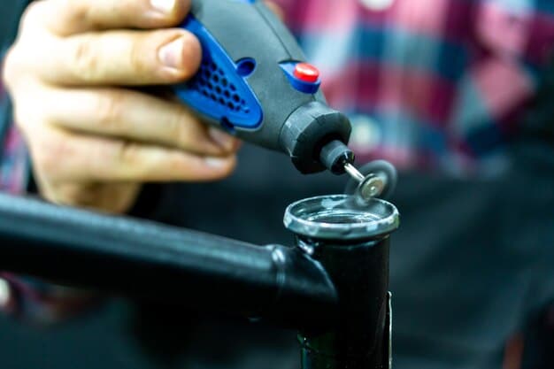 A person using a specialized dent removal tool, possibly a slide hammer or a thermal dent remover, on a car panel. The tool is positioned precisely on the dent, and the person is wearing protective gloves.