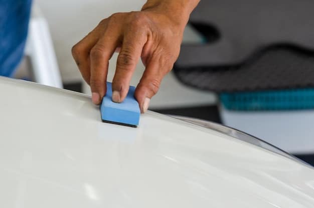 A close-up of a car surface being carefully sanded with fine-grit sandpaper in preparation for a DIY Car Paint Touch-Up: Fix Small Chips and Scratches for a Flawless Finish. The focus is on the smooth transition being created around the damaged area.