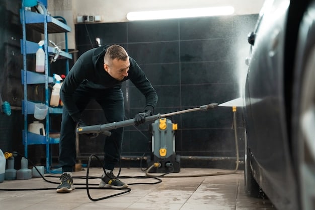 A mechanic thoroughly cleaning the undercarriage of a car with a pressure washer, preparing it for rustproofing treatment. The image emphasizes the importance of pre-treatment cleaning.