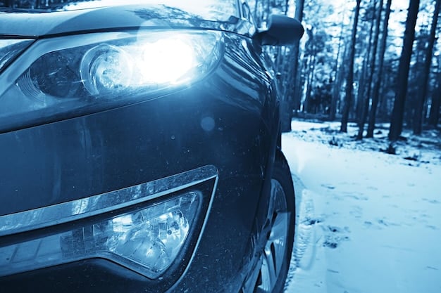 A close-up of a well-maintained car headlight illuminating a snowy road at dusk, with a clear windshield next to it.