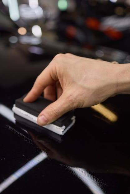 Close-up of a detailer's hands carefully applying ceramic coating to the surface of a new car. The focus is on the smooth application and the glossy result, illustrating the meticulous care involved in new car detailing to protect the paint.
